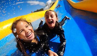 Two female bodysliders enjoying a freestyle slide on the Mega Slip and Slide