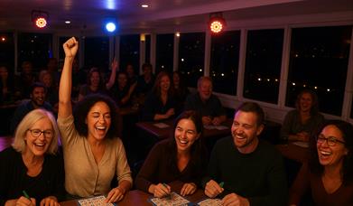 5 people sat playing bingo - very happy and one has an arm in the air