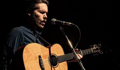 Singer Luke Jackson holding guitar and singing