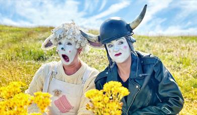 Two clowns, one dressed as a cute sheep and the other dressed as biker cow!