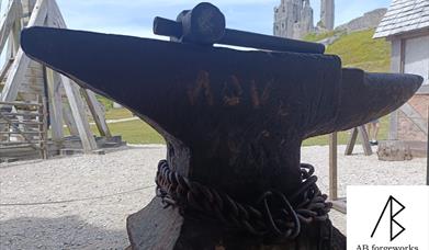 Blacksmithing anvil inside Corfe Castle with the main castle ruins in the background.