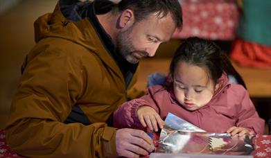 A father helping his daughter decorate a small tree decoration