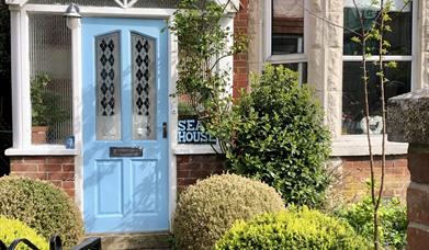 front door painted blue on red brick Edwardian house with glass porch