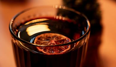 A glass of mulled wine with a fir cone behind it