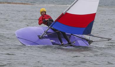 A person sailing a dinghy at Shell Bay Sailing Centre at Studland in Dorset