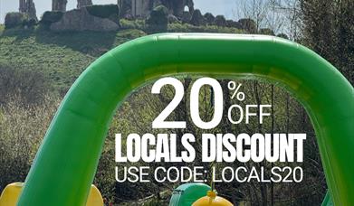 Waterpark inflatables with Corfe Castle in background. Text reads: 20% off Locals Discount