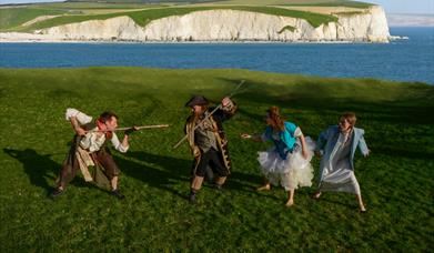 Peter, Hook, Tinker Bell and Wendy play fight on a Dorset cliff side