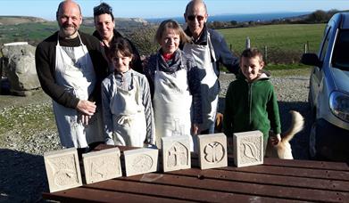 Six people with the stone carvings they have created at Burngate Purbeck Stone Centre near Swanage in Dorset