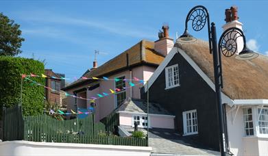 Quaint pink cottage behind iconic thatched cottages on seafront with garden overlooking Lyme Bay.